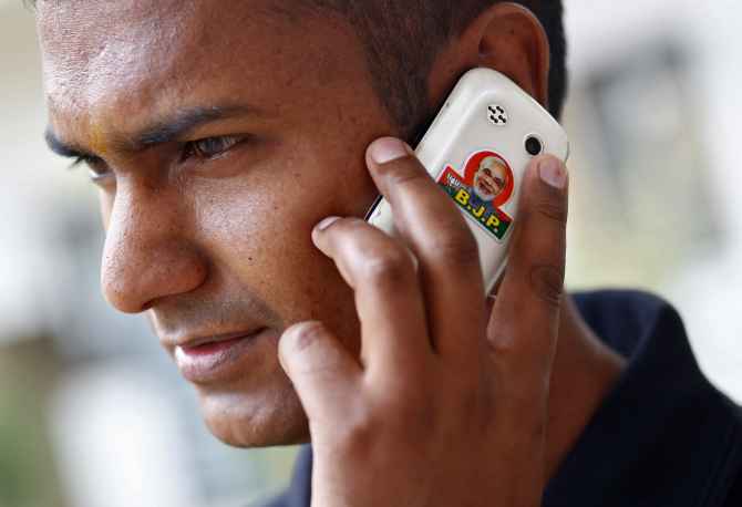 A BJP supporter speaks on his mobile phone with a picture of Narendra Modi, in New Delhi