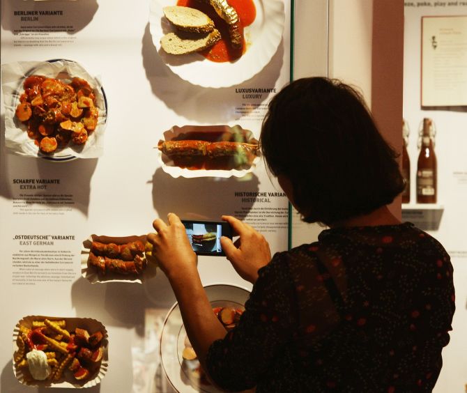A visitor takes a snapshot of different currywurst styles at the museum.