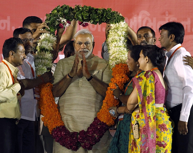 PM elect Narendra Modi wears a garland presented to him by his supporters at a public meeting in Ahmedabad