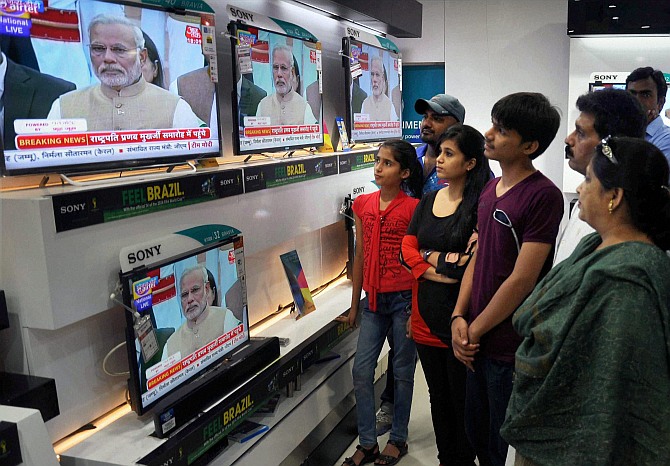 People watching swearing-in ceremony of Prime Minister Narendra Modi on TV sets at a shop 