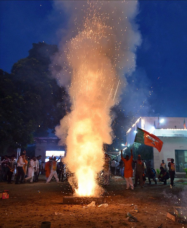 BJP workers celebrate with crackers the swearing-in of Narendra Modi as the Prime Minister at BJP head quater in New Delhi on Monday