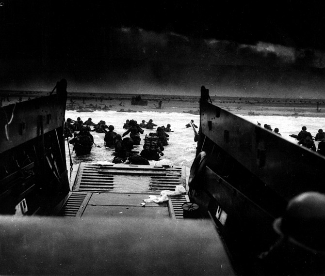 Landing on the coast of France under heavy Nazi machine gun fire are these American soldiers, shown just as they left the ramp of a Coast Guard landing boat