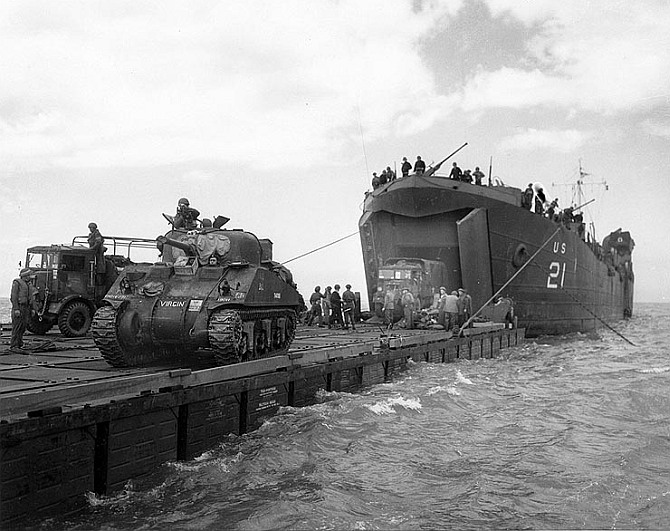 Coast Guard manned USS LST-21 unloads British Army tanks and trucks onto a 'Rhino' barge