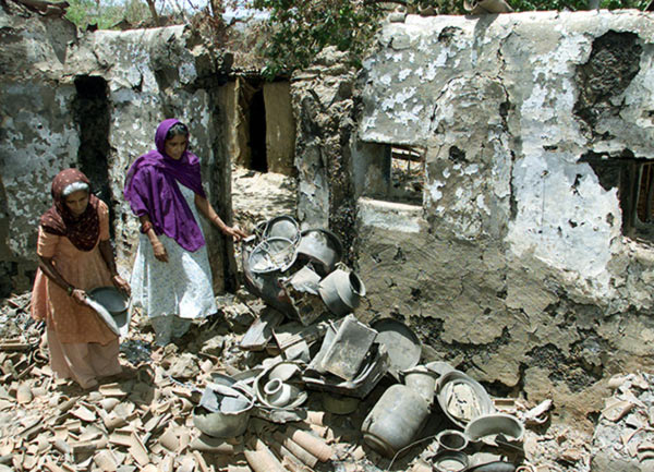 Muslim women rummage through the debris of their house after the Gujarat riots in 2002.