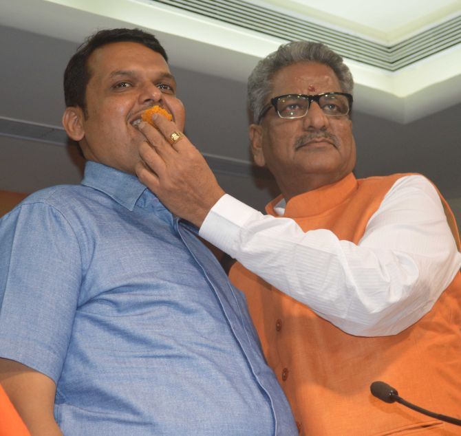 Senior BJP leader O P Mathur feeds state BJP President Devendra Fadnavis a laddoo. Photograph: Deepak Salvi