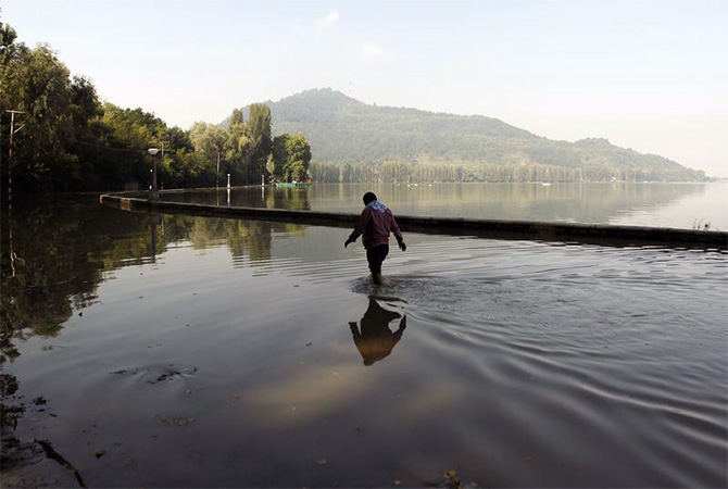 A man wades in flood waters near Dal Lake