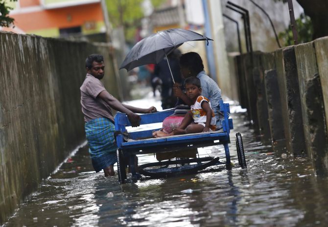 A man carries his family on a rickshaw cart through a flooded street in Chennai last year.