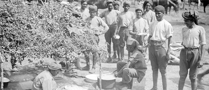 Indian soldiers wait for food at an improvised cookhouse at a camp near Querrieu in July 1916.