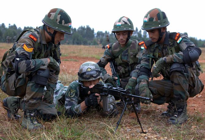 Indian soldiers assist a Chinese trooper fire their weapon.