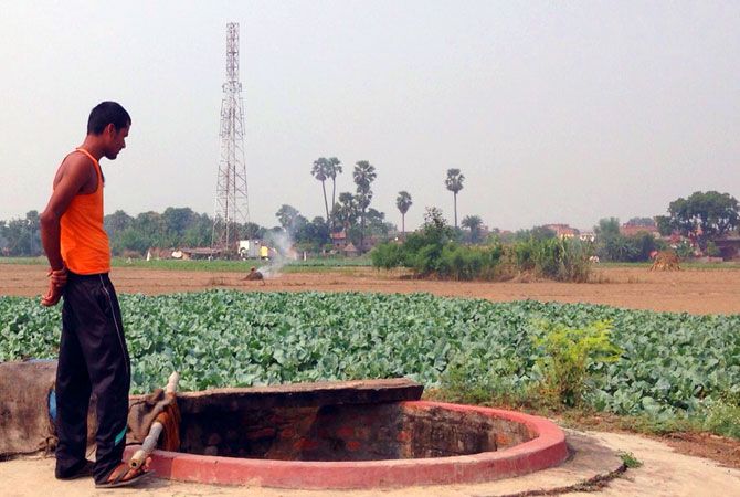 A farmer stands by a well in a field