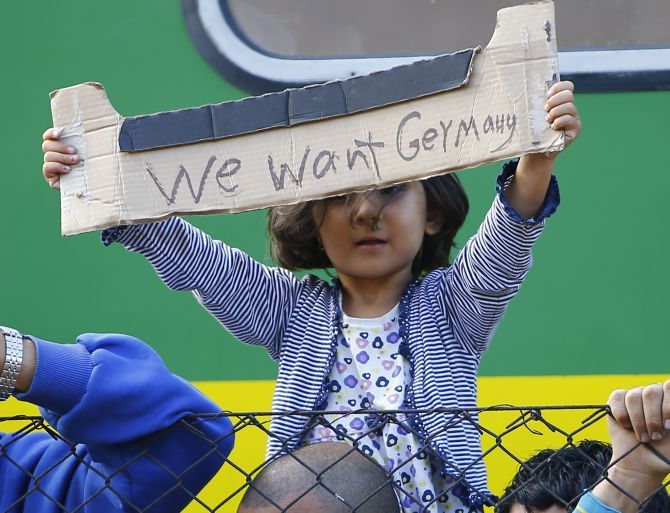 A young migrant girl holds up a sign during a protest in front of a train at Bicske railway station, Hungary.