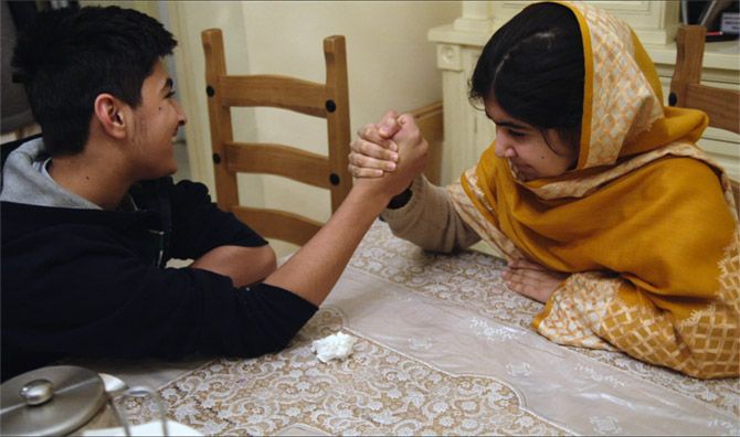 Nobel Laureate Malala Yousafzai armwrestles with her younger brother at her home in England.