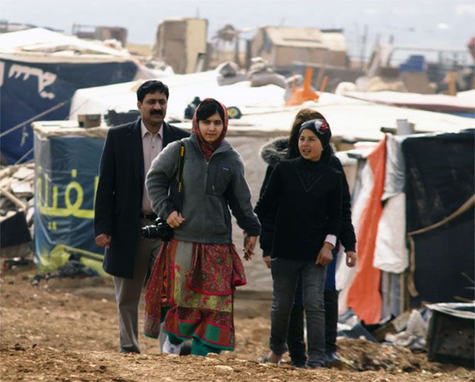 Ziauddin Yousafzai and Malala Yousafzai and Syrian refugee Rimah at a Syrian refugee tent camp in Jordan, February 17, 2014.. 