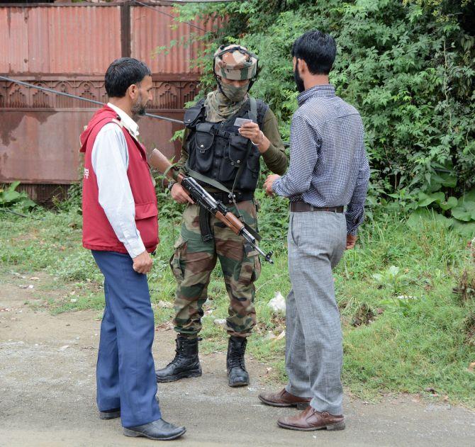 A jawan checks the identity cards of Kashmiris on the 51st day of curfew following Burhan Wani's death in downtown Srinagar, August 28, 2016. Photograph: Umar Ganie for Rediff.com