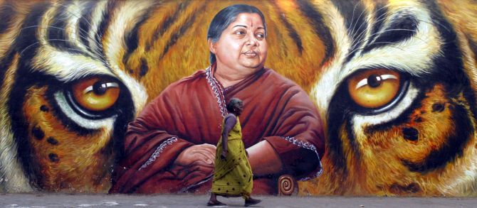 A woman walks past a Jayalalithaa poster