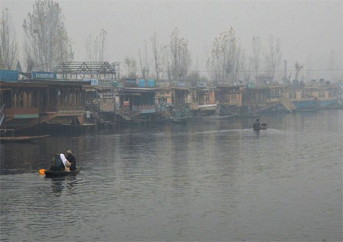 Srinagar residents make their way through the thick fog that has descended over the Dal Lake
