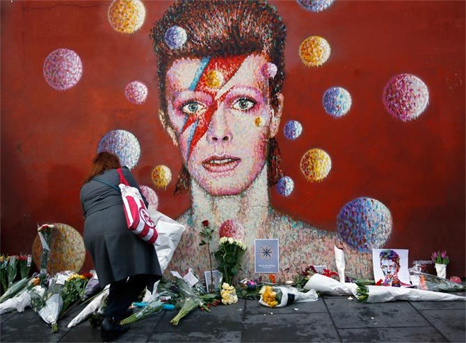 A woman leaves a bouquet at a mural of David Bowie in Brixton, south London, January 11, 2016. Photograph: Stefan Wermuth/Reuters