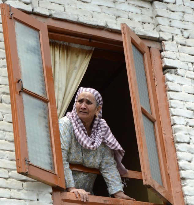 A woman looks out during street protests in Kashmir