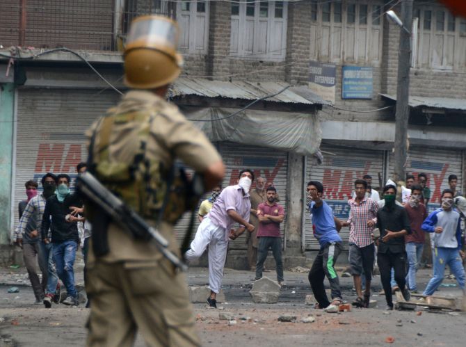 Protesters hurl stones amid tear gas smoke fired by the police during a protest in Srinagar. Photograph: Umar Ganie