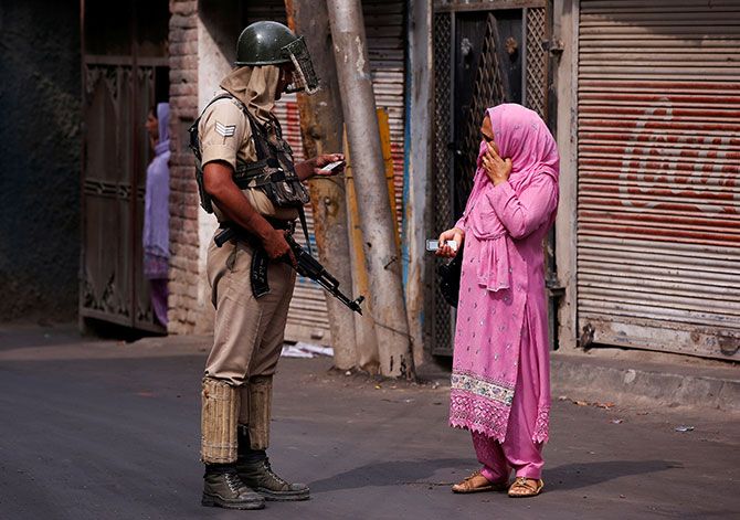 A woman shows her identity proof to a soldier in Kashmir