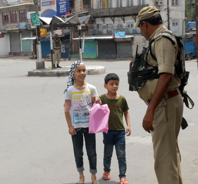 Security personnel question children on a deserted street in Srinagar. Photograph: Umar Ganie
