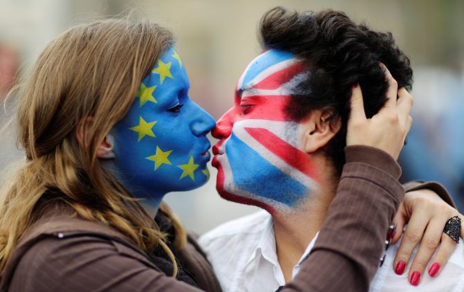 Two activists with the EU flag and Union Jack painted on their faces kiss each other in front of Brandenburg Gate to protest against the British exit from the European Union.