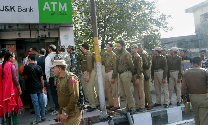 JAMMU: Jammu & Kashmir police personnel stand with other people in a queue outside an ATM. Photograph: PTI Photo
