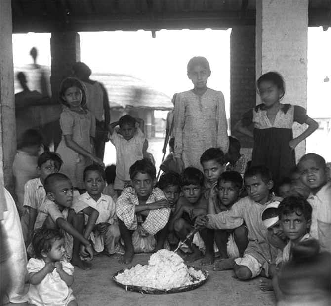 At the Kingsway refugee camp, children help themselves to the rice provided for their meal.