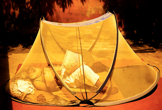 A man uses a hand fan as he prepares to sleep under a mosquito net on a footpath in New Delhi August 21, 2014. Photo: Anindito Mukherjee/Reuters 