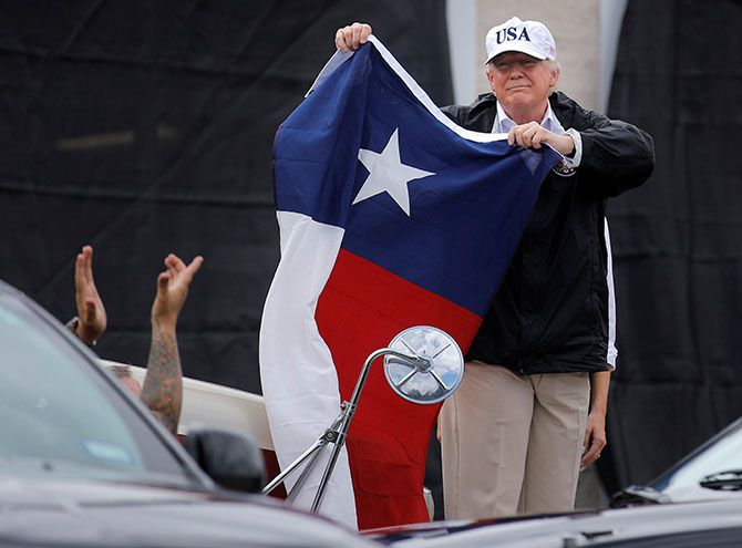 Donald Trump holds a flag of the state of Texas after receiving a briefing on Harvey relief efforts at a fire station in Corpus Christi, Texas, August 29, 2017.