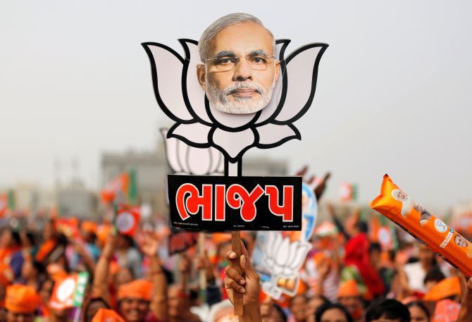 A Modi supporter holds up a cut-out of a lotus, the BJP's symbol at a rally.