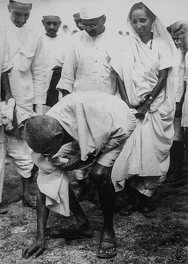 Mahatma Gandhi at Dandi, picking salt on the beach at the end of the salt march, April 5, 1930. Behind him is his second son Manilal