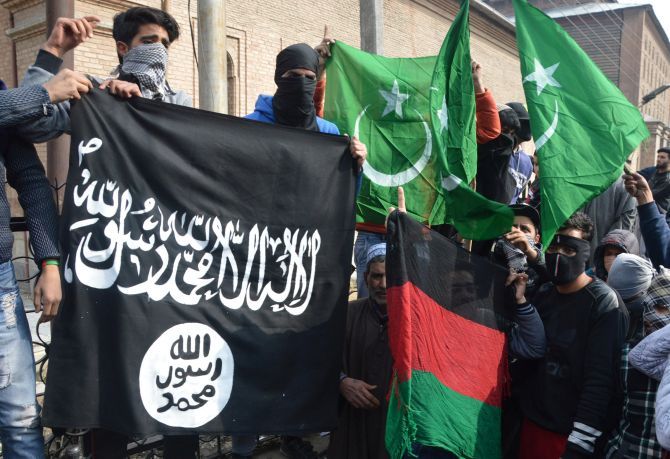 Masked Kashmiri youth brandish Islamic State and Pakistan flags during a protest in Srinagar. Photograph: Umar Ganie