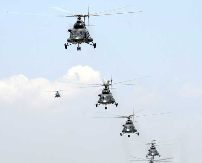 Mi-171 transport helicopters and Z-9 multi-purpose helicopters lift off in formation from a military airfield