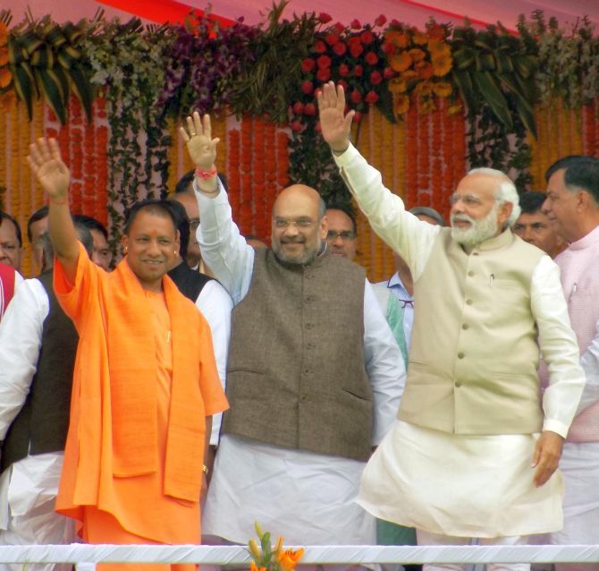 UP CM Yogi Adityanath, BJP president Amit Shah and PM Narendra Modi wave to the crowds after the swearing-in ceremony.