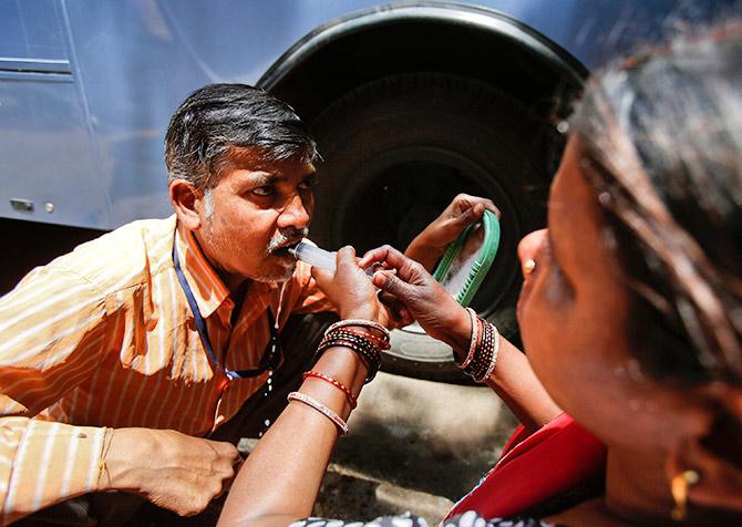 Ramesh Chandra Rathod, 40, who suffers from cancer, is helped by his wife as he rinses his mouth with a syringe after being treated at the Tata Memorial Centre, Mumbai. Photograph: Vivek Prakash/Reuters