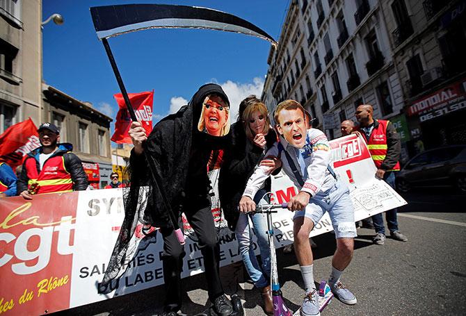 Demonstrators wearing masks of Marine Le Pen and Emmanuel Macron.