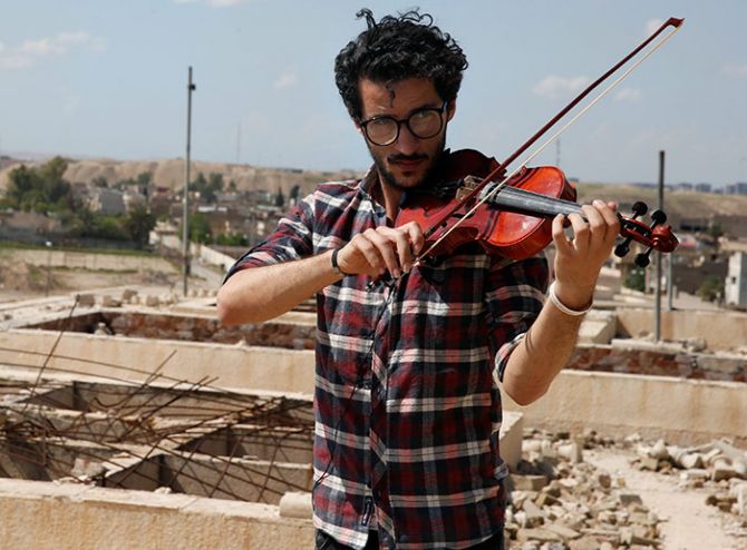 Ameen Mukdad, a violinist from Mosul, Iraq, who lived under ISIS rule for two-and-a-half years where they destroyed his musical instruments, performs at the Nabi Yunus shrine in eastern Mosul, April 19, 2017, after the town was liberated. Photograph: Muhammad Hamed/Reuters