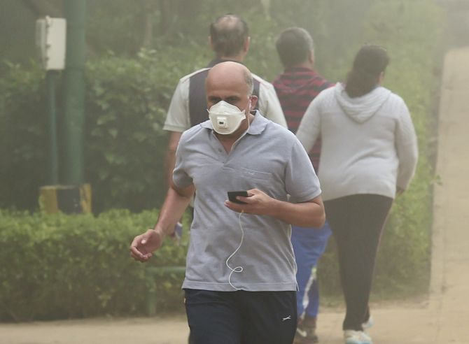 A man wearing an anti-pollution mask jogs through smog at Lodhi Garden, New Delhi. Photograph: Kamal Kishore/PTI Photo