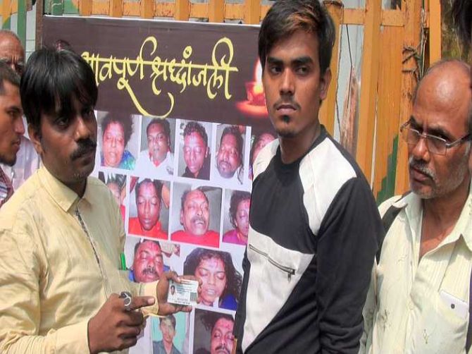 Shaikh Mohammed Shakil's elder brother Sadiq (in yellow) showing his Aadhar card to prove that his brother's photograph in the collage behind him, and numbered 18, was not his brother. Taamil (in black tee), who is elder to Shakil, also works in one of the garment outlets at Elphinstone Road station