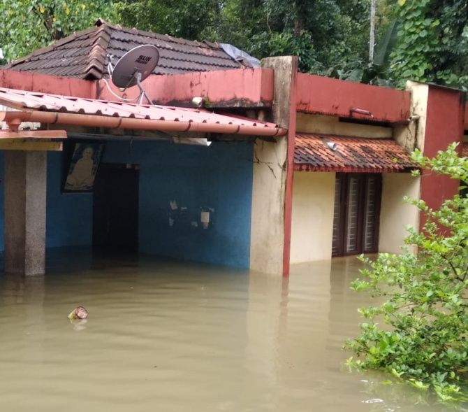 A portrait of Sree Narayana Guru watches over the flooded waters swirling through Prakash's home