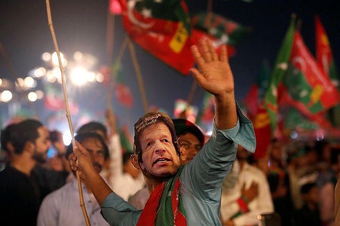 A supporter of Imran Khan wears a mask of the Pakistan Tehreek-e-Insaf leader and dances to party songs during a campaign rally July 22, 2018. Photograph: Akhtar Soomro/Reuters