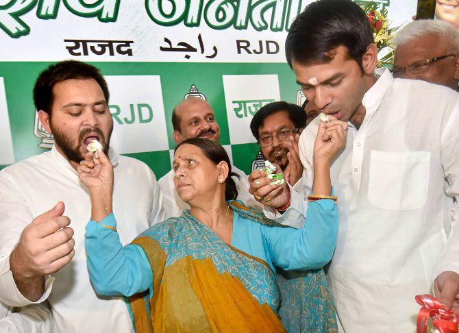 Former Bihar CM Rabri Devi feeds her sons Tejaswi Yadav, left, and Tej Partap Yadav, right, cake to celebrate her husband Lalu Prasad Yadav's 71st birthday in Patna, June 11, 2018. Photograph: PTI Photo