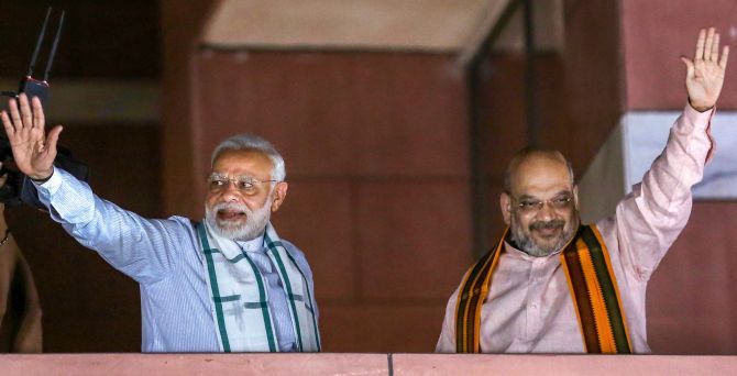 Prime Minister Narendra D Modi and Bharatiya Janata Party President Amit A Shah wave to party workers gathered at the BJP headquarters after the Karnataka assembly election result, May 15, 2018. Photograph: PTI Photo