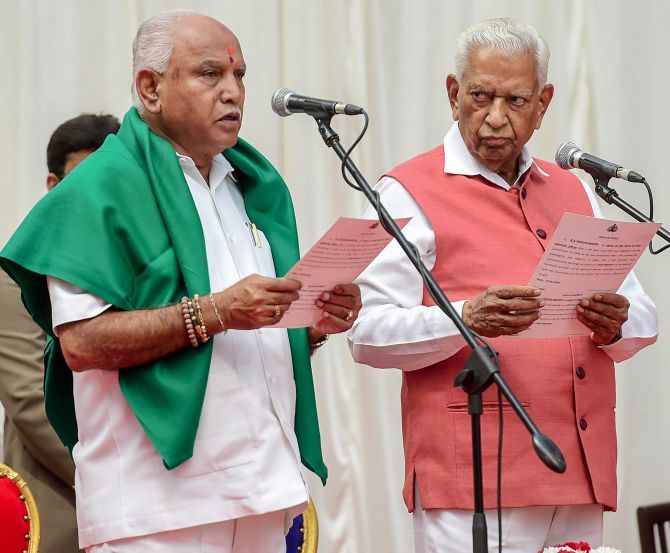 Karnataka Governor Vajubhai Vala, right, administers the oath of office to Bookanakere Siddalingappa Yeddyurappa as chief minister, May 17, 2018. Photograph: Shailendra Bhojak/PTI Photo