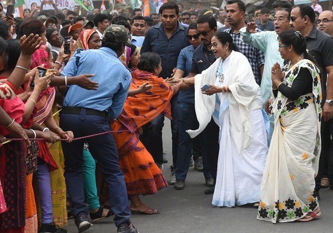 TMC supremo and Chief Minister Mamata Banerjee shake hand with her supporters during a road show in Shantipur. Photograph: ANI Photo
