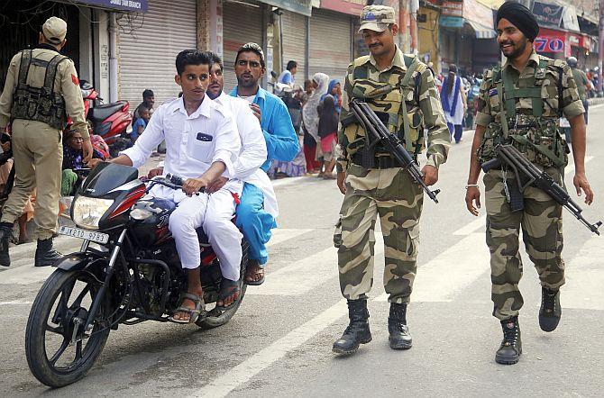 CRPF personnel patrol a street near a mosque before Eid al-Adha prayers. 