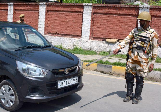 A security person stops a vehicle for checking in Srinagar. 