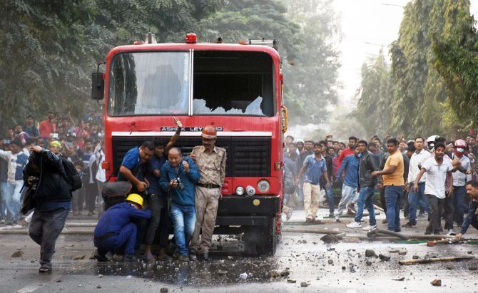 Firefighters and media personnel seek shelter behind a fire brigade vehicle during a protest against the Citizenship (Amendment) Act 2019 in Guwahati. Photograph: ANI Photo