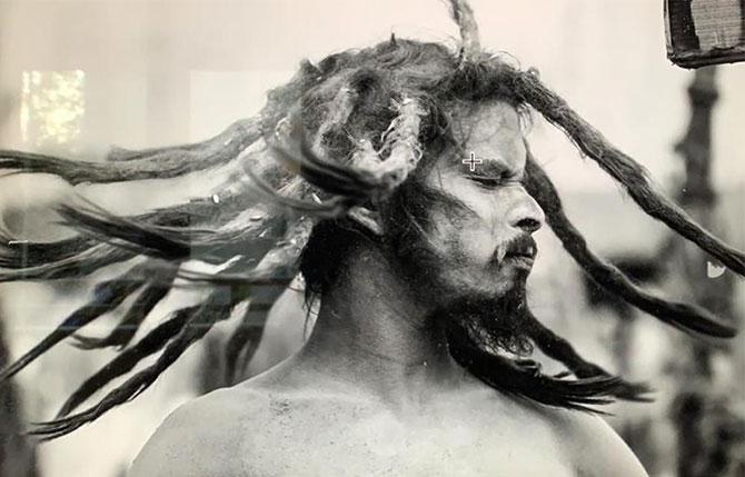 A sadhu swings his dreadlocks after a bath at the ghat